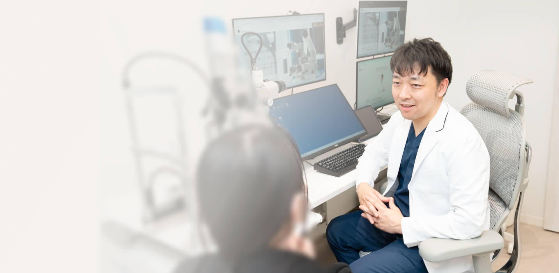 複数のモニターを背に、笑顔で患者に説明する様子
